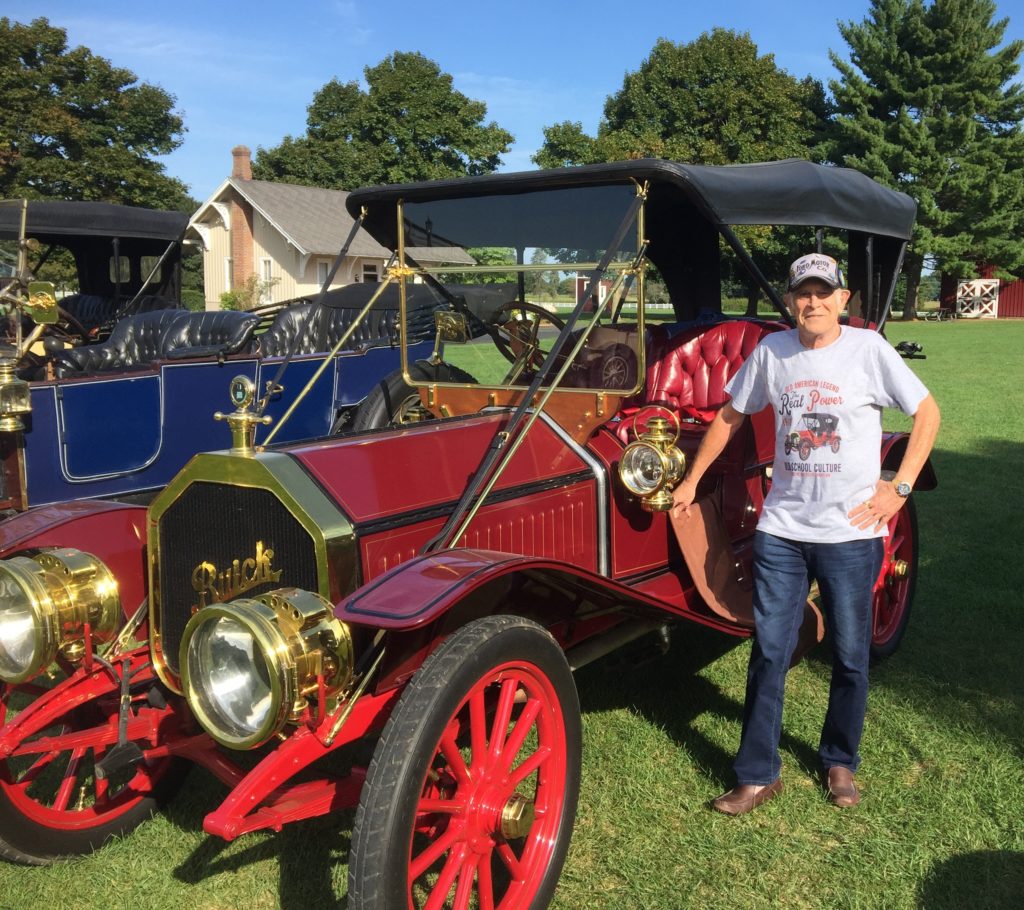 A man next to his red 1910 Buick Model 16 Surrey